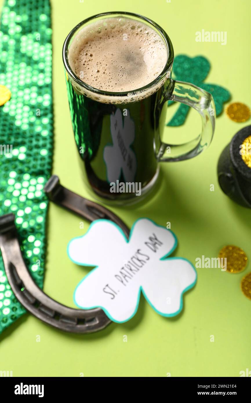 Tazza di birra scura con ferro di cavallo, cravatta e cartolina festiva per St. Festa del giorno di Patrick su sfondo verde Foto Stock