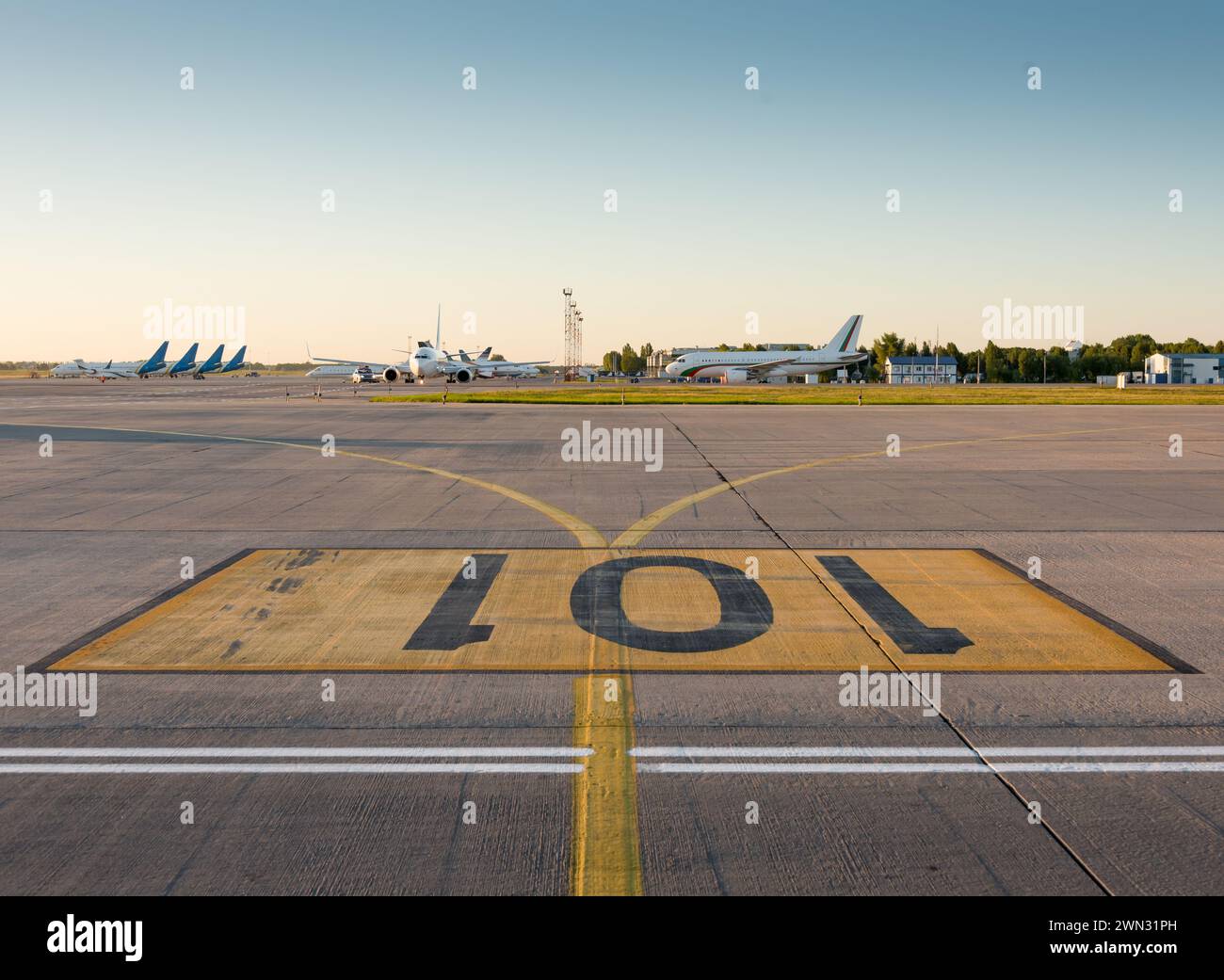 Aeroporto 101. Parcheggio per gli aerei numero 101 - segnaletica stradale dipinta sul grembiule dell'aeroporto al tramonto. Numeri neri su rettangolo giallo. Foto Stock