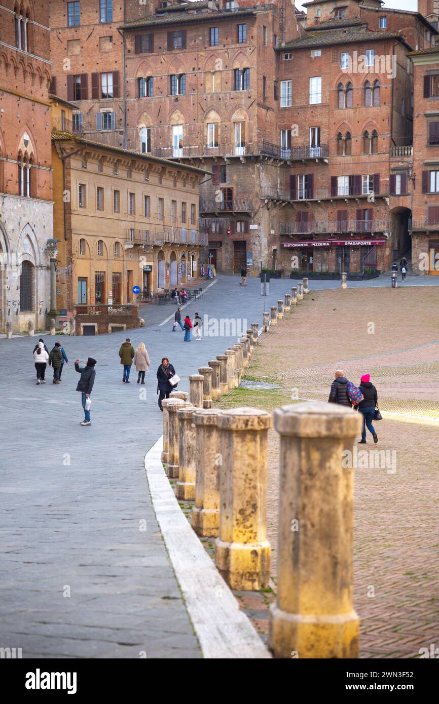 Siena, Italia - 08 gennaio 2024: Una donna turistica seduta sulla piazza di campo che gode del sole in inverno Foto Stock