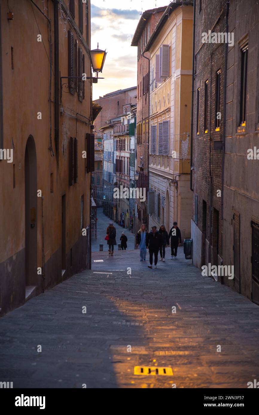 Siena, Italia – 08 gennaio 2024: Turisti che camminano per strada durante il tramonto Foto Stock