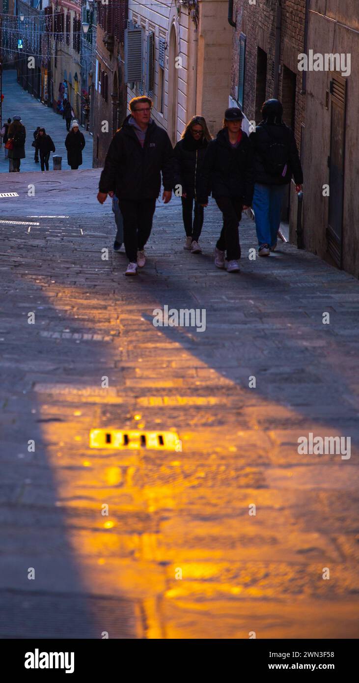 Siena, Italia – 08 gennaio 2024: Turisti che camminano per strada durante il tramonto Foto Stock