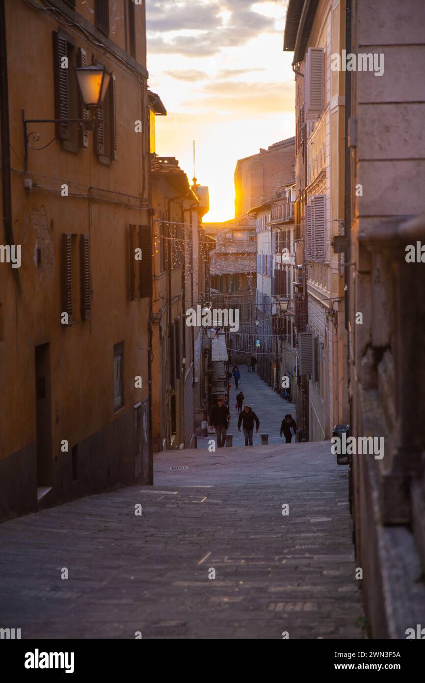 Siena, Italia – 08 gennaio 2024: Turisti che camminano per strada durante il tramonto Foto Stock