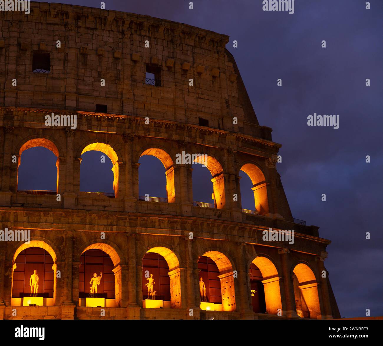 La parete del colosseo con luce dorata di notte a Roma, Italia Foto Stock