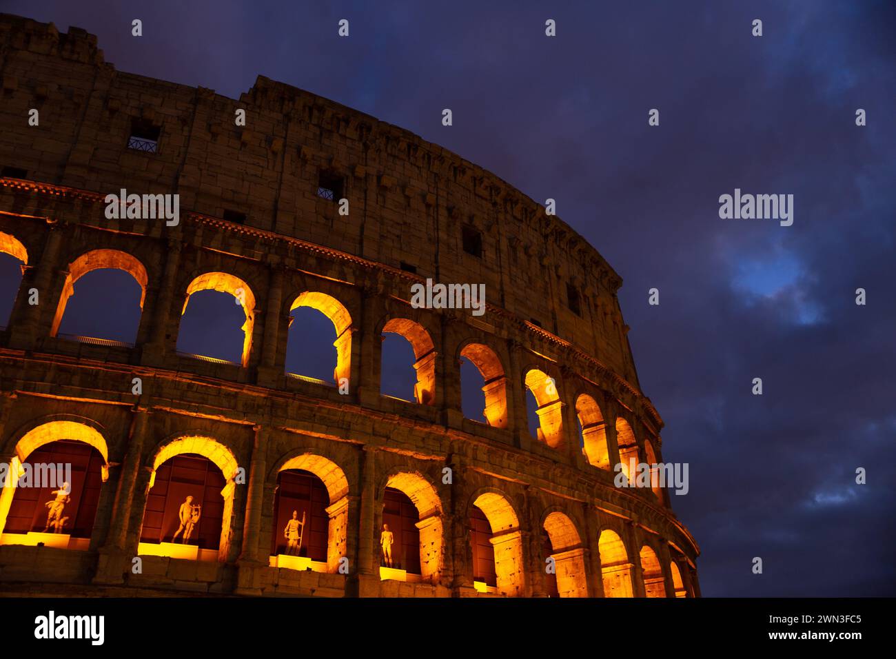 La parete del colosseo con luce dorata di notte a Roma, Italia Foto Stock