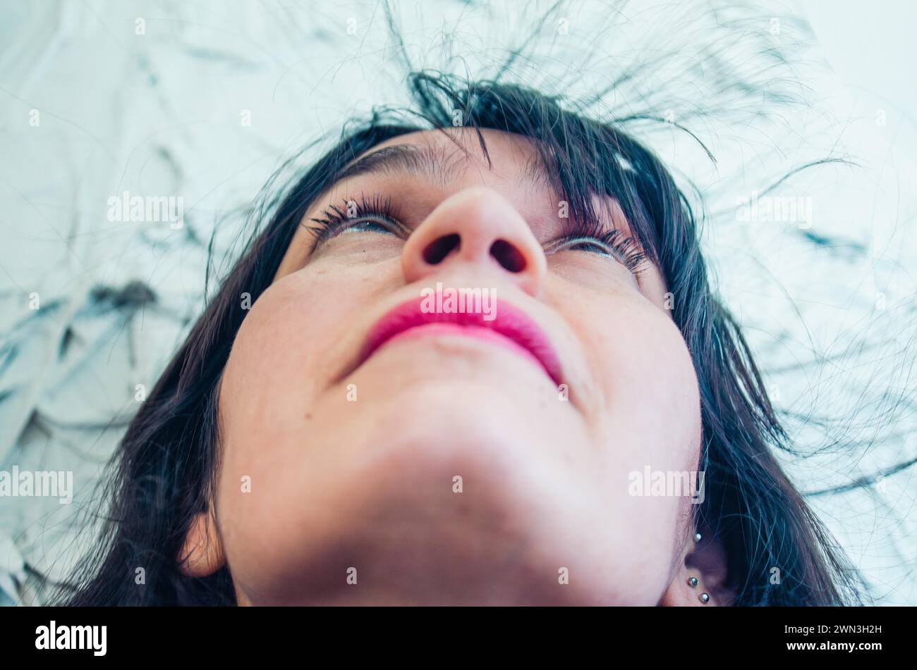 Un'inquadratura bassa di una donna che guarda verso l'alto con una piuma nei capelli, performance artistiche, danza giocosa Foto Stock