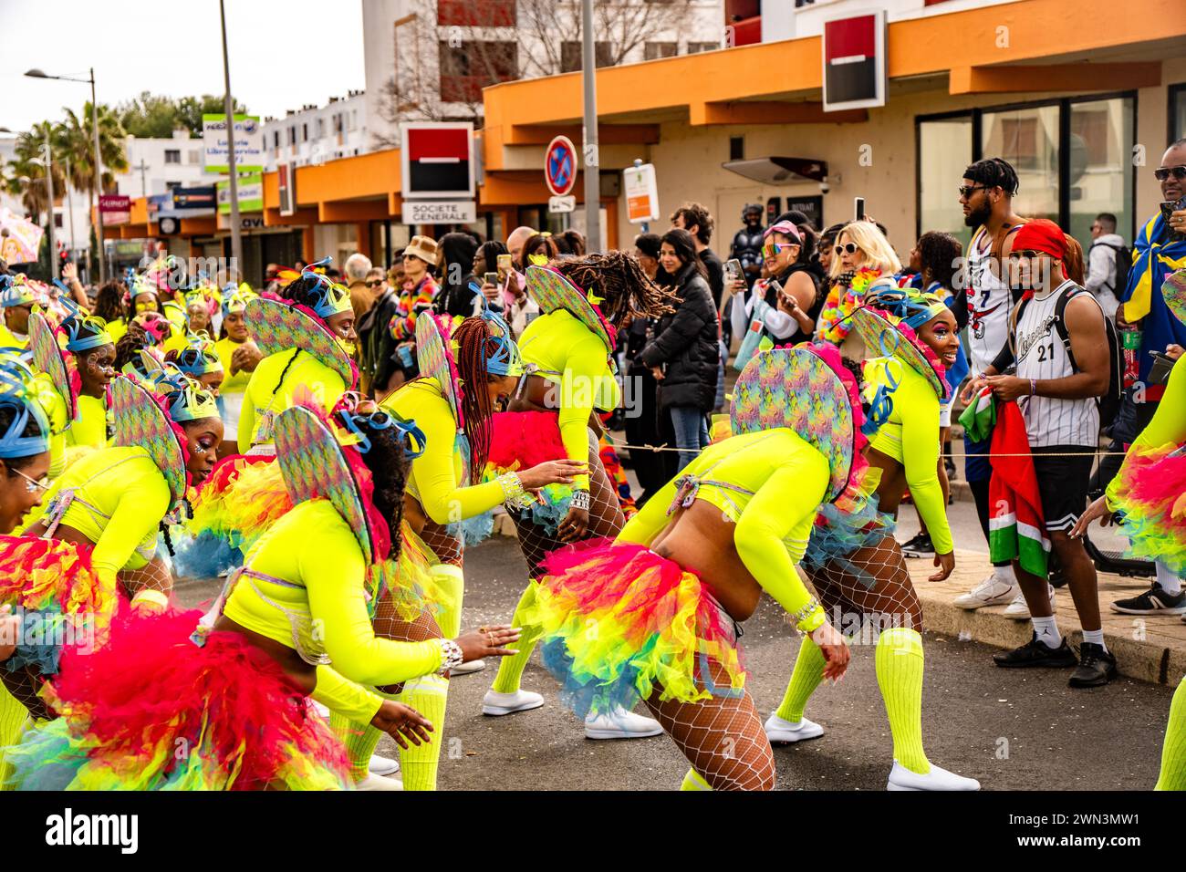 Un gruppo di persone in costumi vivaci che camminano per la strada Foto Stock