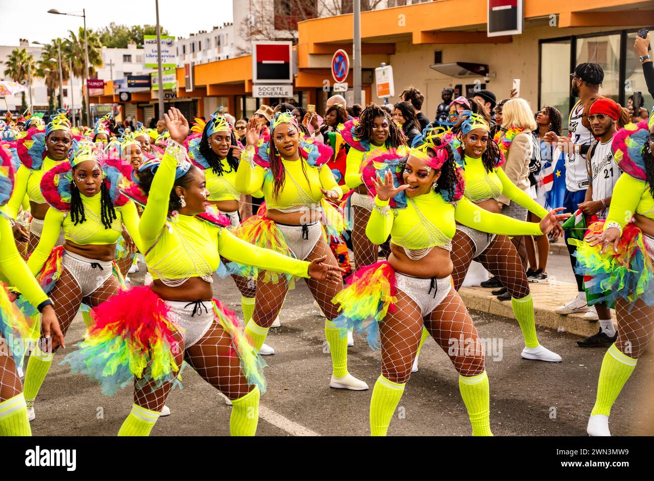 Le donne in vivaci costumi al neon eseguono una danza vivace in un carnevale, Montpellier Carnival Foto Stock