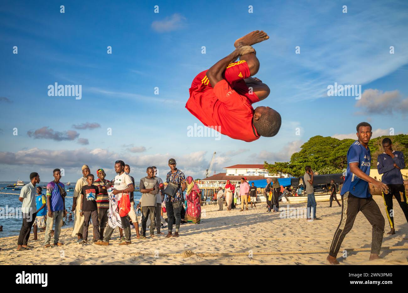 Un giovane esegue acrobazie nel tardo pomeriggio sulla spiaggia di Stone Town, Zanzibar, Tanzania. Foto Stock