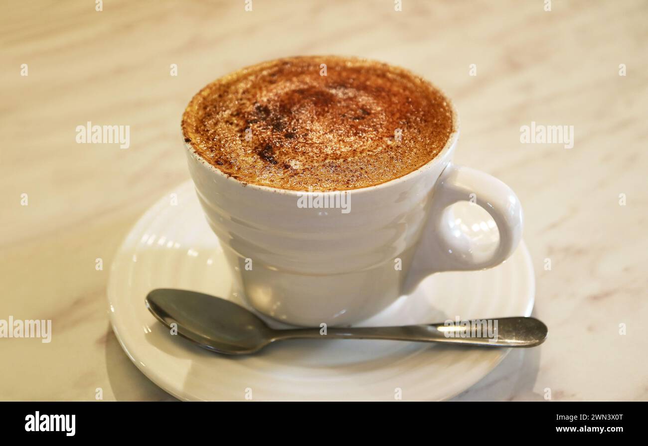 Tazza di appetitoso caffè cappuccino schiumoso su un tavolo bianco Foto Stock