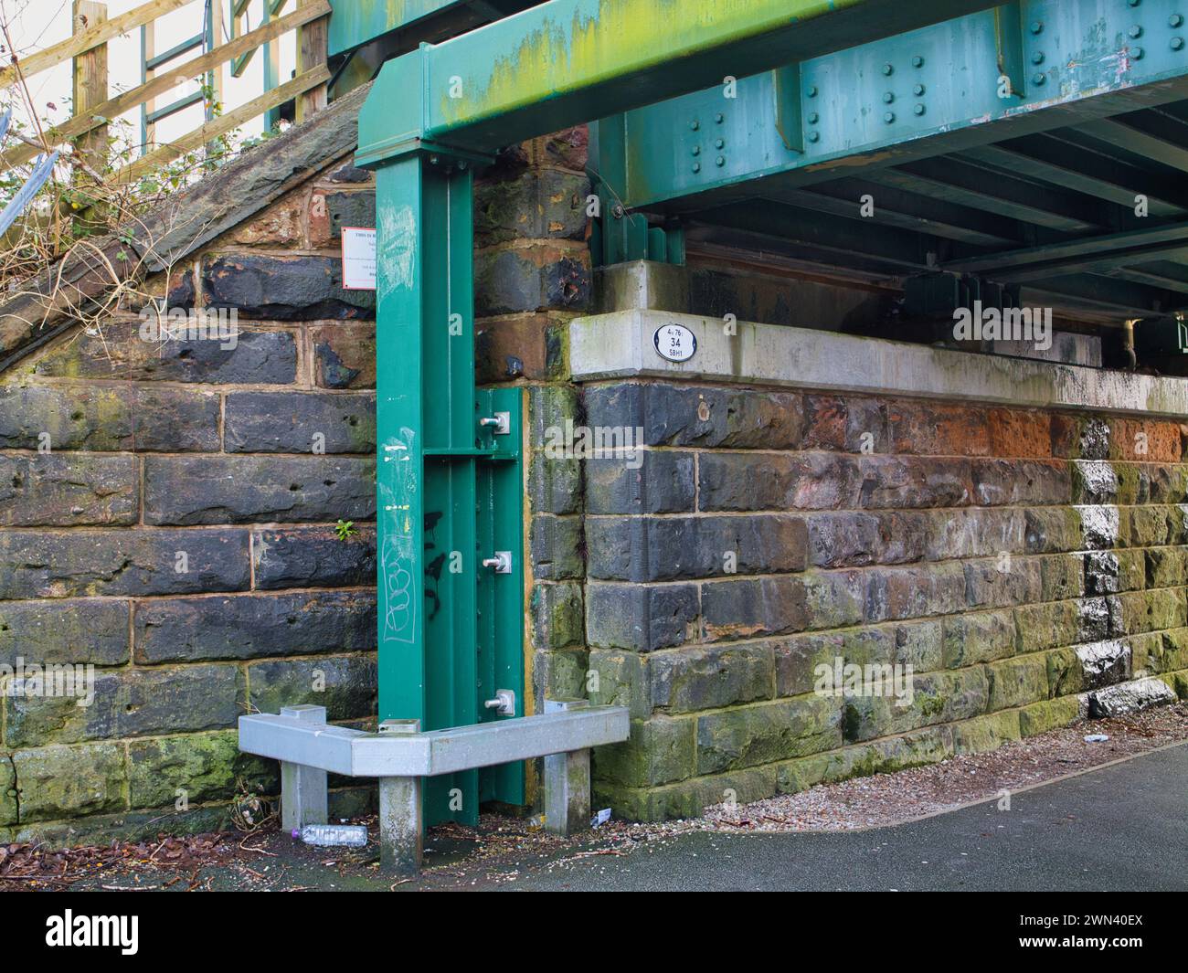 St Helens, Regno Unito - 4 gennaio 2024: Un telaio in acciaio verniciato di verde fornisce protezione contro gli urti a un ponte ferroviario in pietra arenaria a St Helens, Merseyside Foto Stock