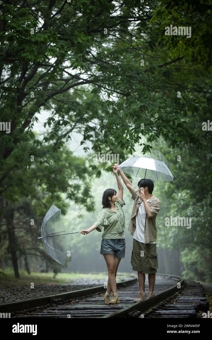 Coppia giovane ombrelli azienda Foto Stock