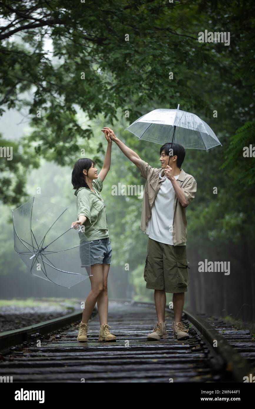 Coppia giovane ombrelli azienda Foto Stock