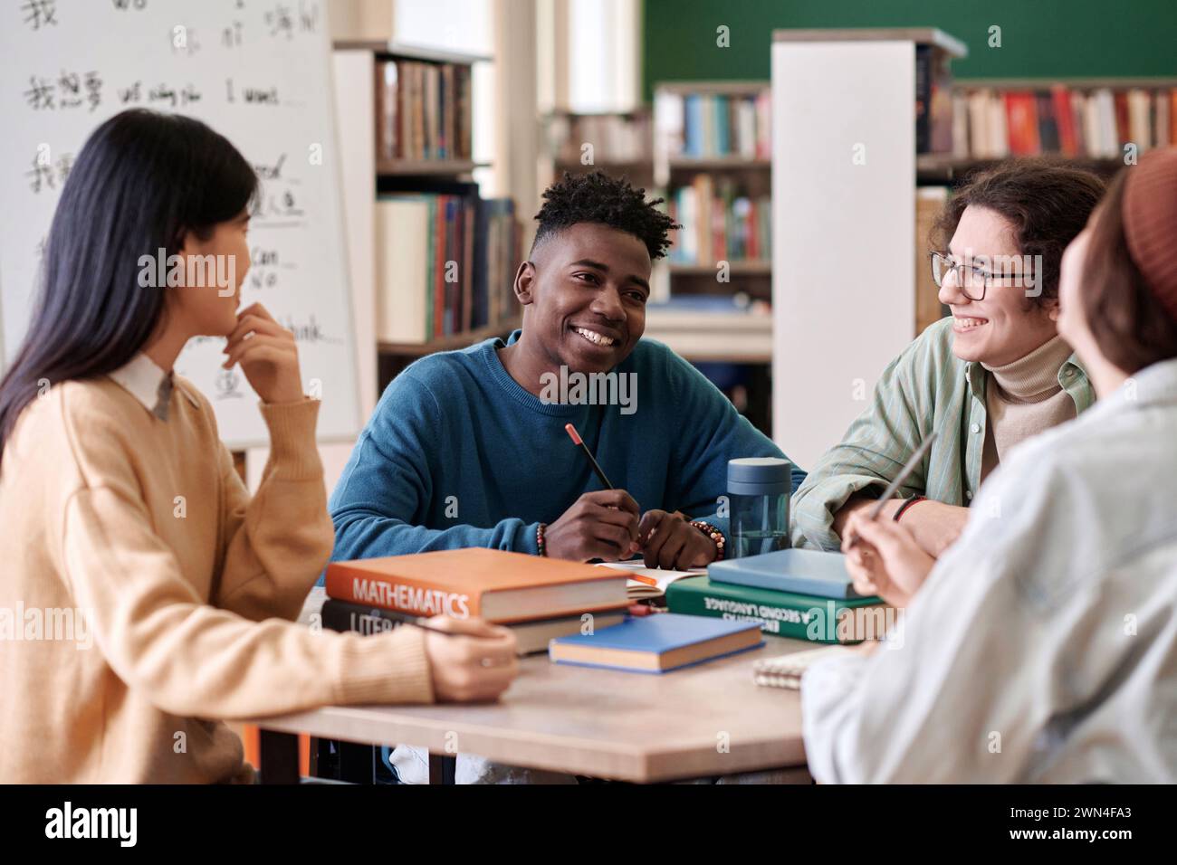 Ritratto di un giovane nero sorridente durante una discussione di gruppo con gli studenti nella biblioteca universitaria Foto Stock