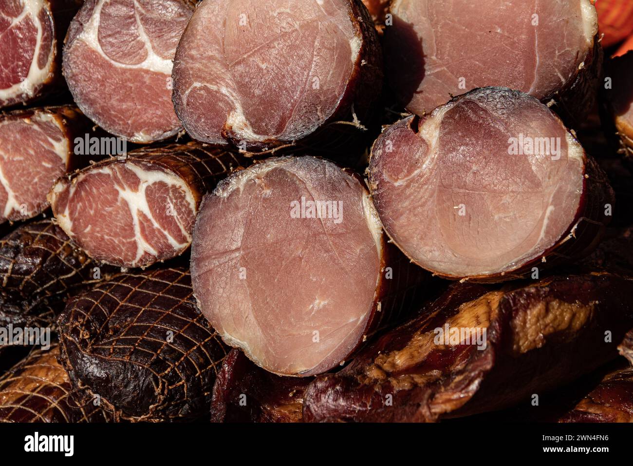 Deliziosi pezzi di carne affumicata esposti per la vendita nel mercato presentato in vendita in un mercato agricolo nel villaggio di Kacarevo, festival del bacon gastronomico Foto Stock