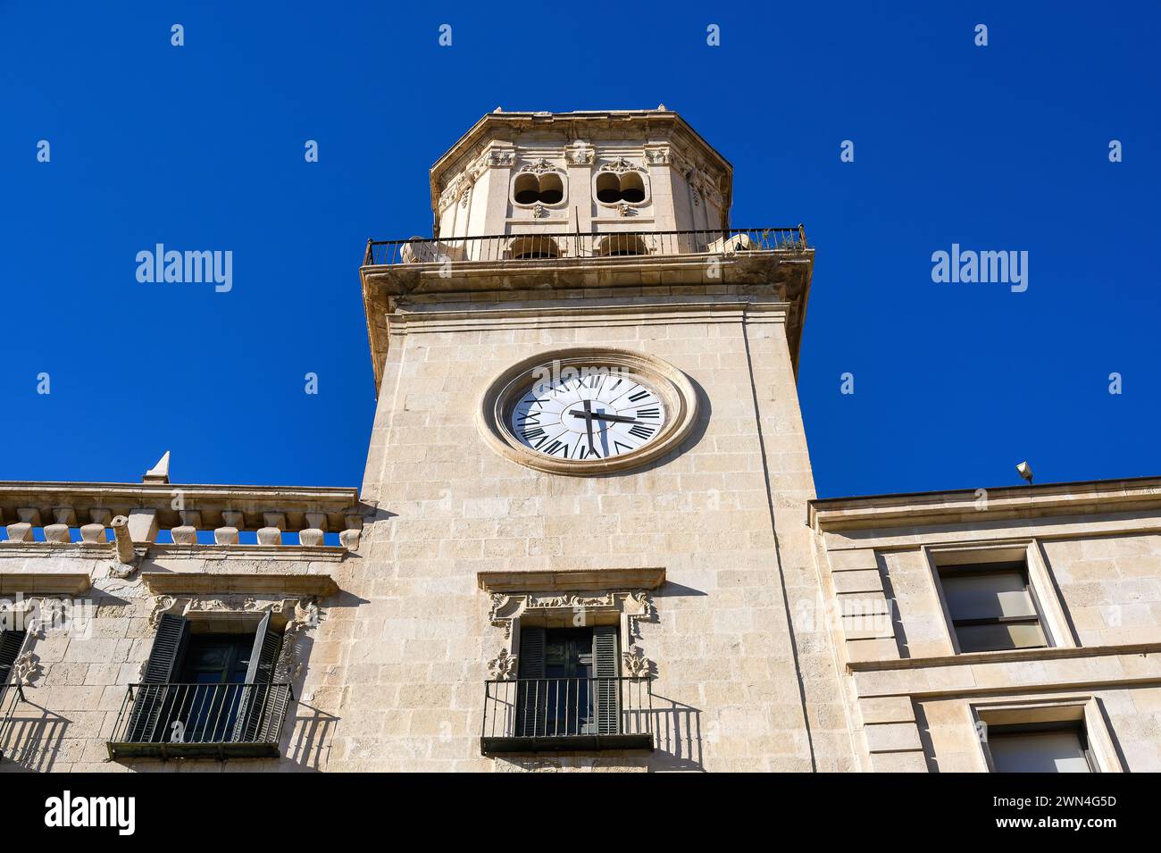 Vista ad angolo basso della torre dell'orologio nella facciata medievale dell'edificio del Municipio, Alicante, Spagna Foto Stock