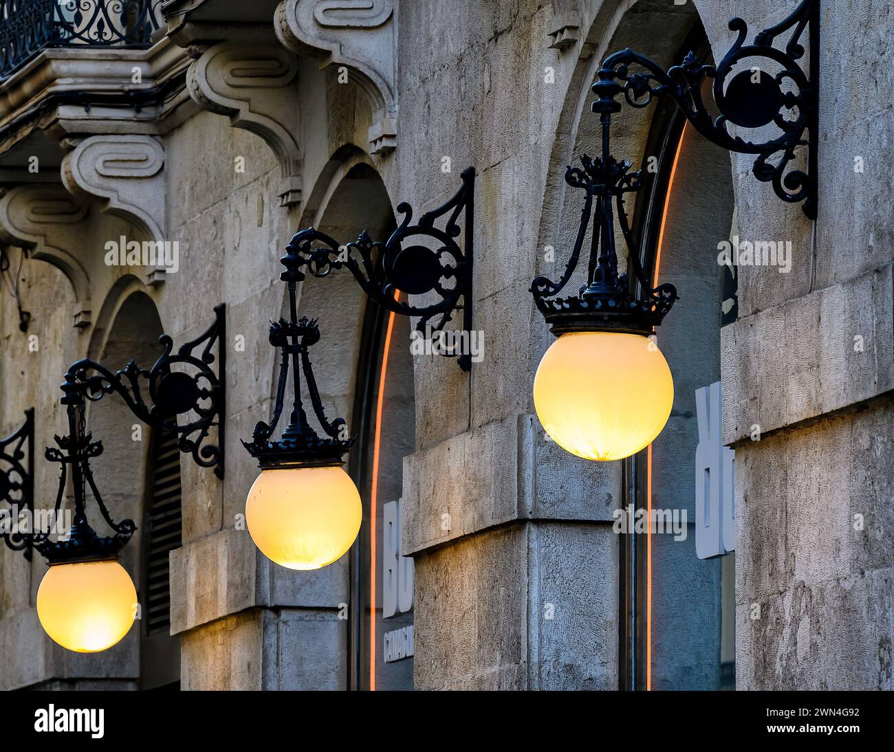 Luci stradali illuminate sulla facciata di un edificio coloniale con pareti in pietra, Alicante, Spagna Foto Stock
