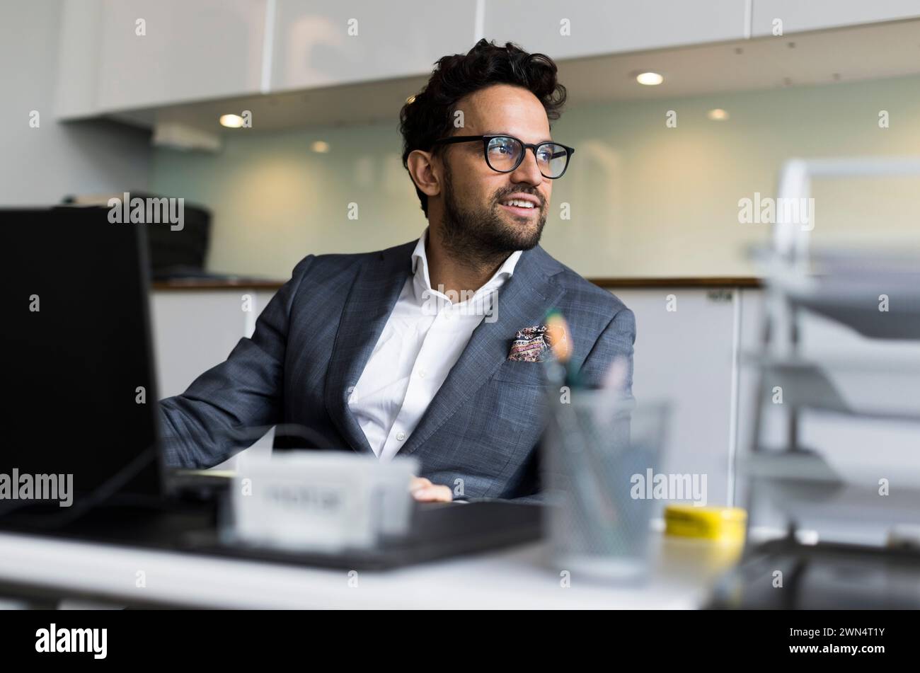 Un agente immobiliare maschile premuroso seduto alla scrivania in ufficio Foto Stock