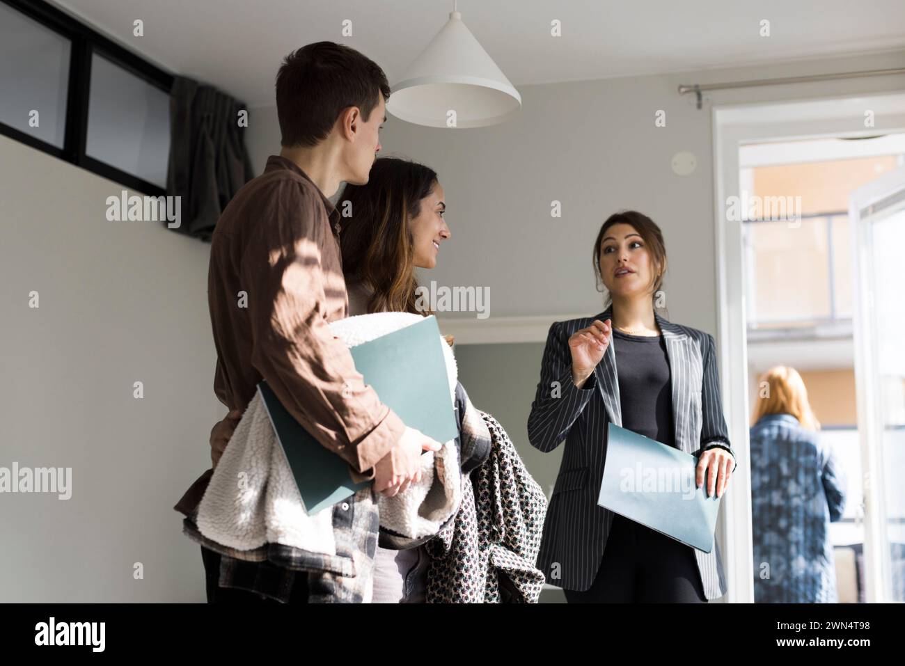 Vista a basso angolo di una donna agente immobiliare che assiste i clienti durante la visita della casa Foto Stock