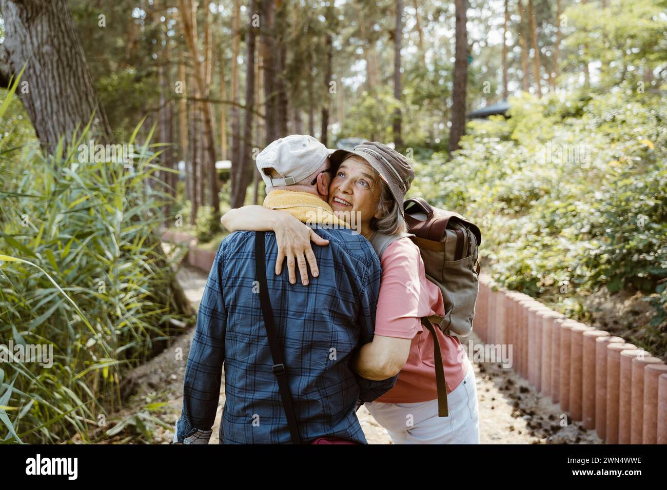 Donna anziana felice che abbraccia un uomo mentre fa escursioni nella foresta Foto Stock