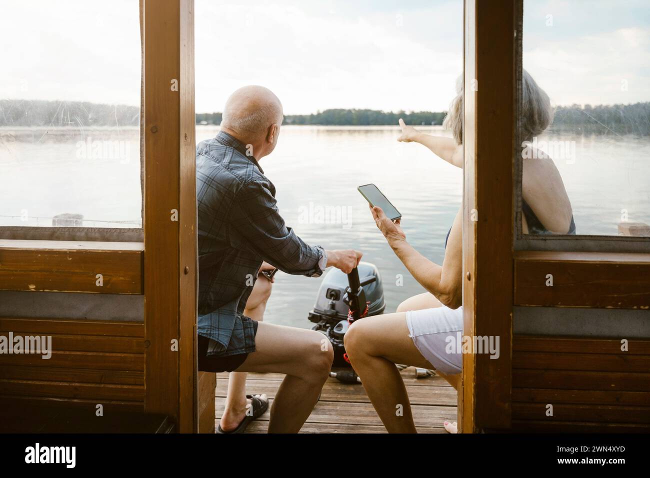 Una coppia anziana con uno smartphone seduto sulla casa galleggiante Foto Stock