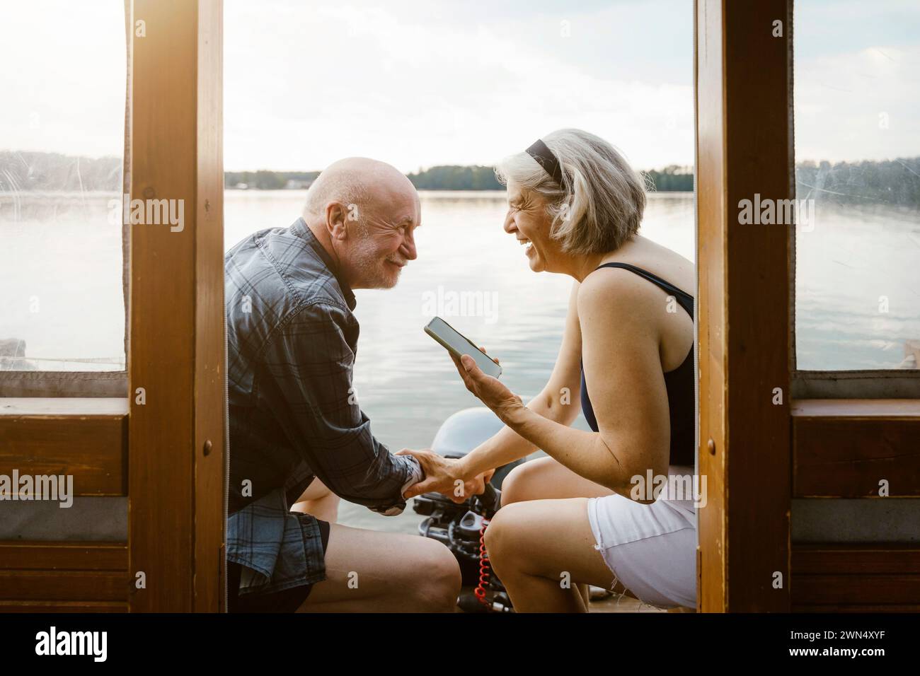 Felice coppia anziana con uno smartphone seduto sulla casa galleggiante Foto Stock