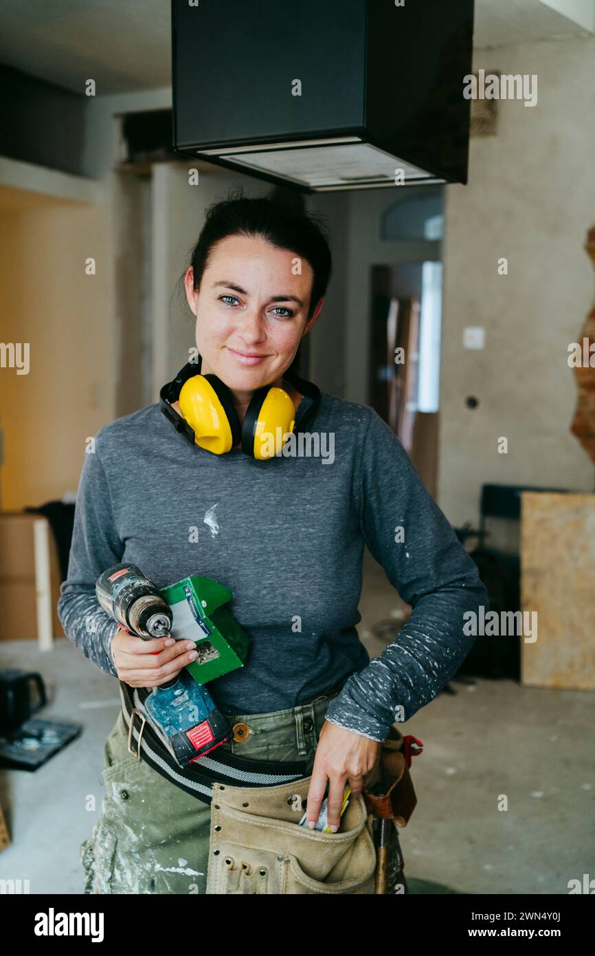 Ritratto di una donna sorridente responsabile delle costruzioni con attrezzature in cantiere Foto Stock