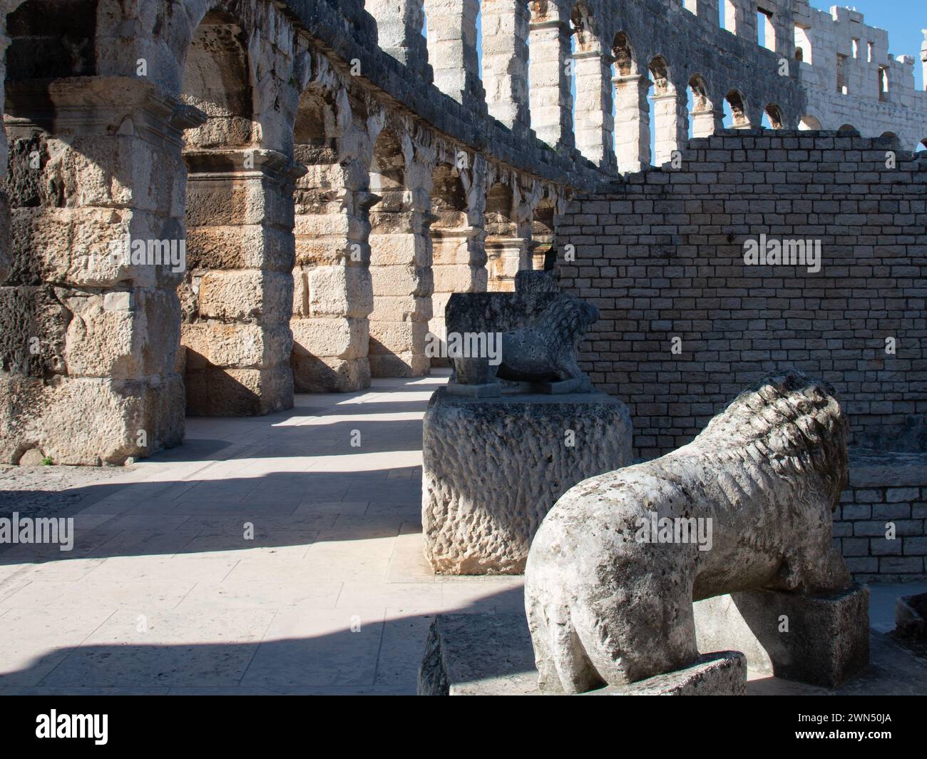 Due leoni di pietra in piedi accanto agli archi dell'antico anfiteatro di Pola, Pola, Istria, Croazia 2018 Foto Stock