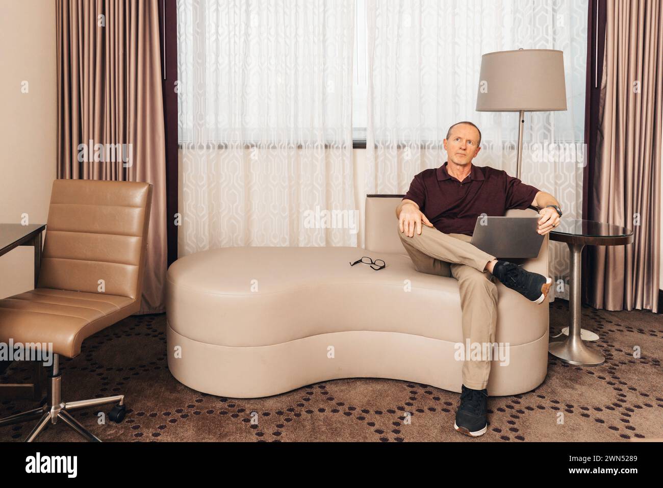 uomo in un abbigliamento casual per lavoro che lavora su un computer portatile in una camera d'hotel Foto Stock