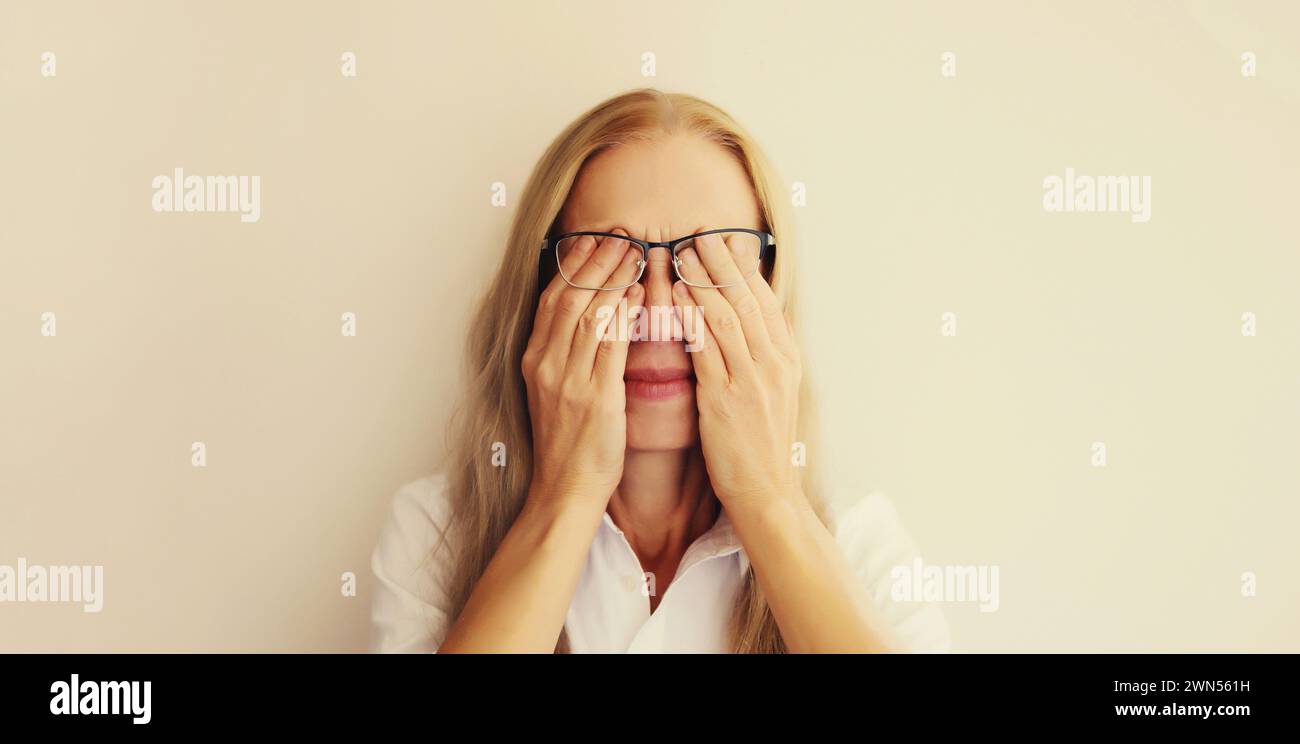Dipendente di una donna stanca e affaticata che si sfrega agli occhi affetto da tensione oculare, sindrome dell'occhio secco o mal di testa Foto Stock