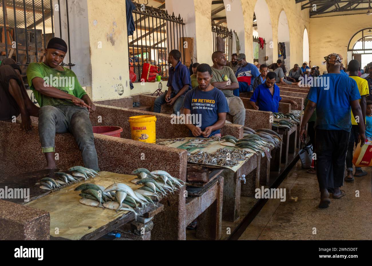 Gli uomini vendono pesce all'interno del mercato di Stone Town, Zanzibar, Tanzania Foto Stock