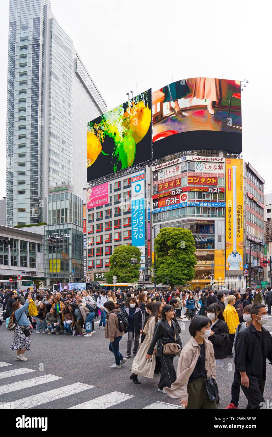 Cartelloni pubblicitari digitali e pedoni che utilizzano lo Shibuya Scramble Crossing, l'intersezione pedonale trafficata a Shibuya nella capitale Tokyo, Giappone Foto Stock
