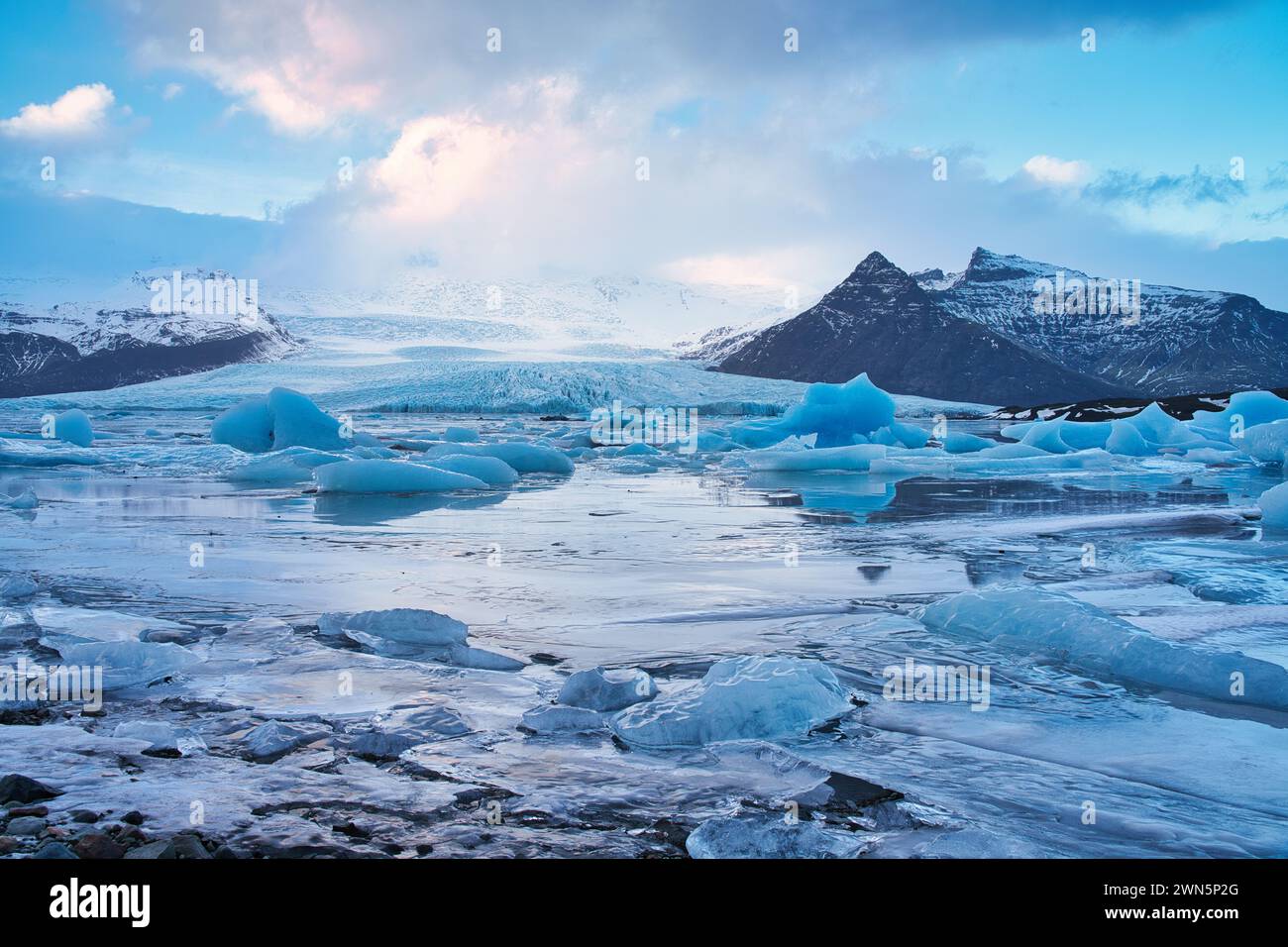 Lago glaciale con ormeggi ghiacciati e acqua ghiacciata con montagne sullo sfondo Foto Stock