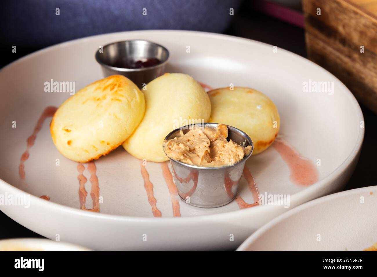 Colazione slava. Syrniki servito con marmellata di lamponi e latte condensato bollito. Primo piano con messa a fuoco morbida selettiva Foto Stock