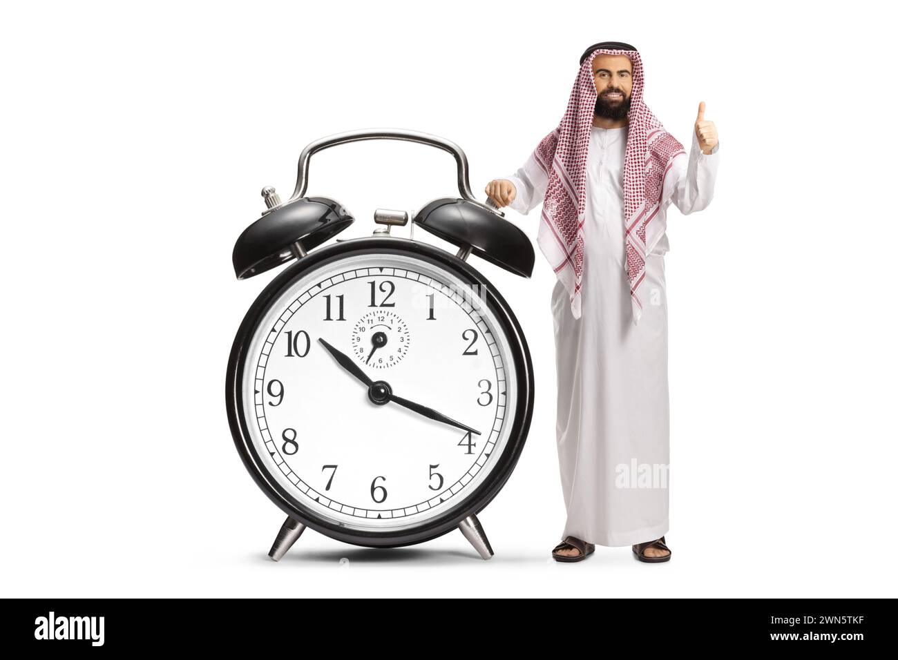 Uomo arabo saudita in abiti etnici con una grande sveglia con gesti su isolato su sfondo bianco Foto Stock
