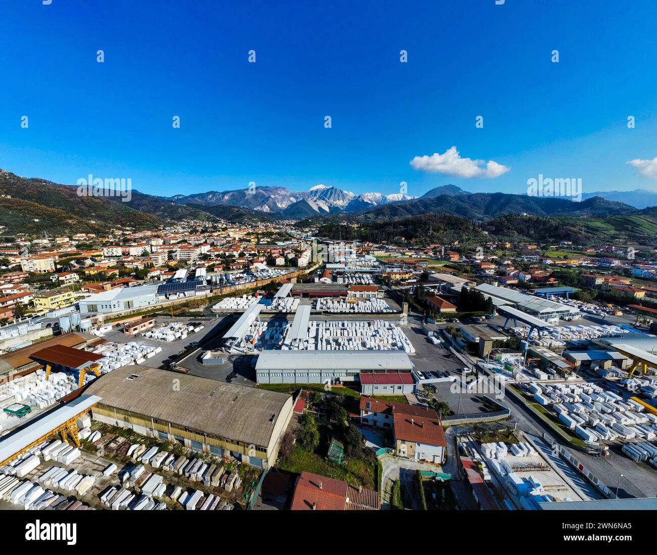 Immagine aerea di Carrara, Toscana, vista grandangolare con cielo blu sullo sfondo le montagne delle Alpi Apuane, l'industria della lavorazione del marmo, i blocchi di marmo Foto Stock