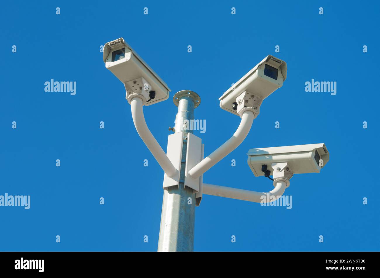 Tre telecamere di sicurezza a circuito chiuso montate su un palo contro il cielo blu Foto Stock