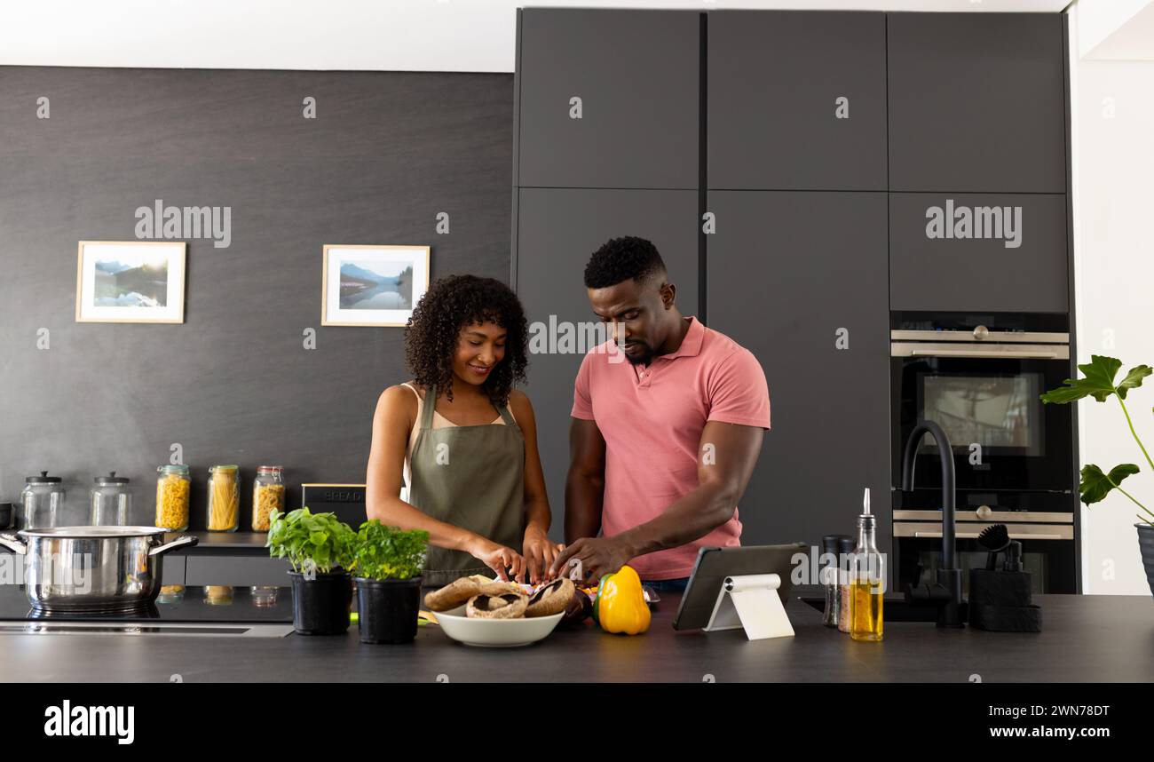 Una coppia afroamericana birazziale sta cucinando insieme in una cucina moderna a casa Foto Stock