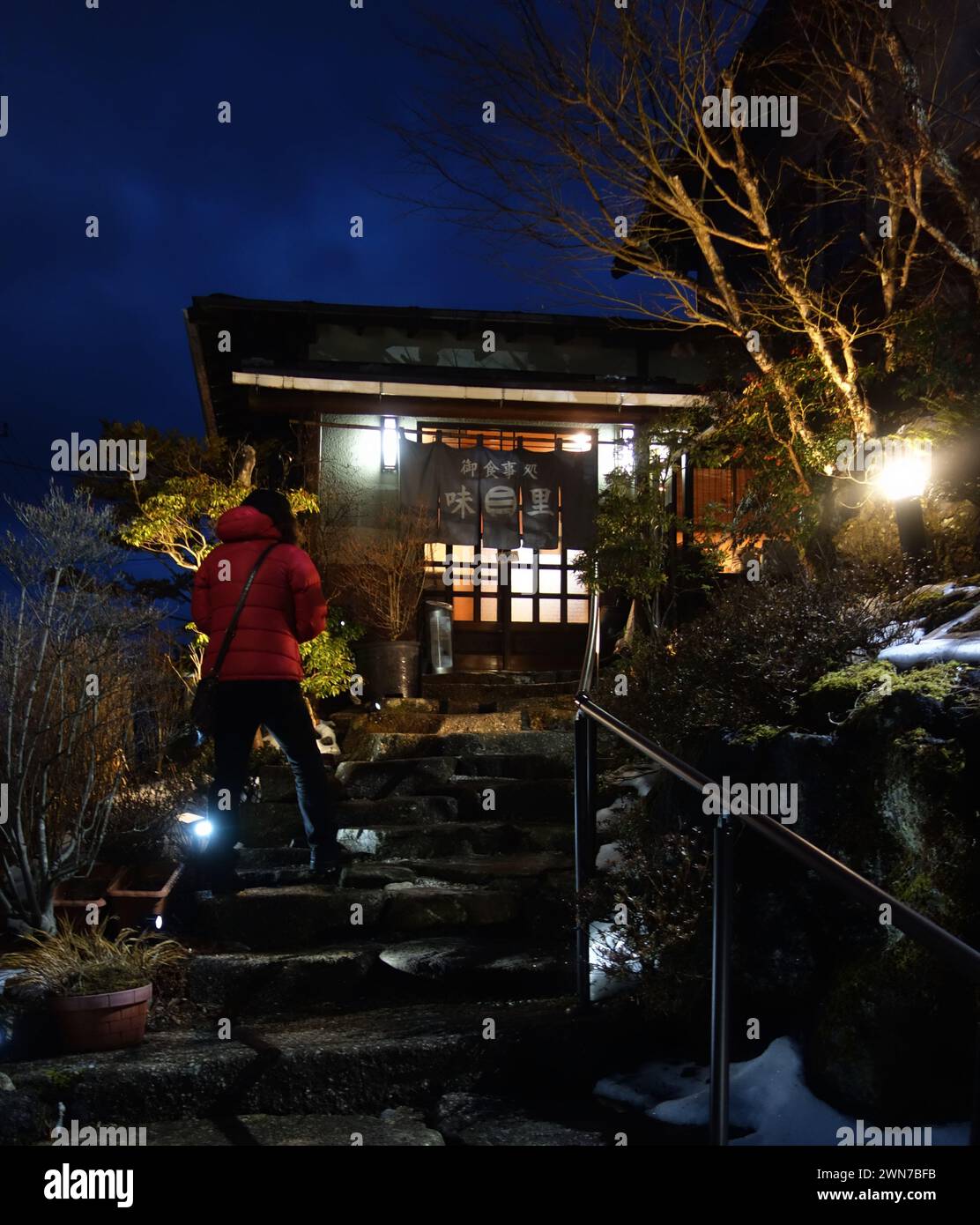 Persona in giacca rossa che entra nel tradizionale ristorante Izakaya, nel lago Yamanaka, nella regione del monte Fuji, in Giappone Foto Stock