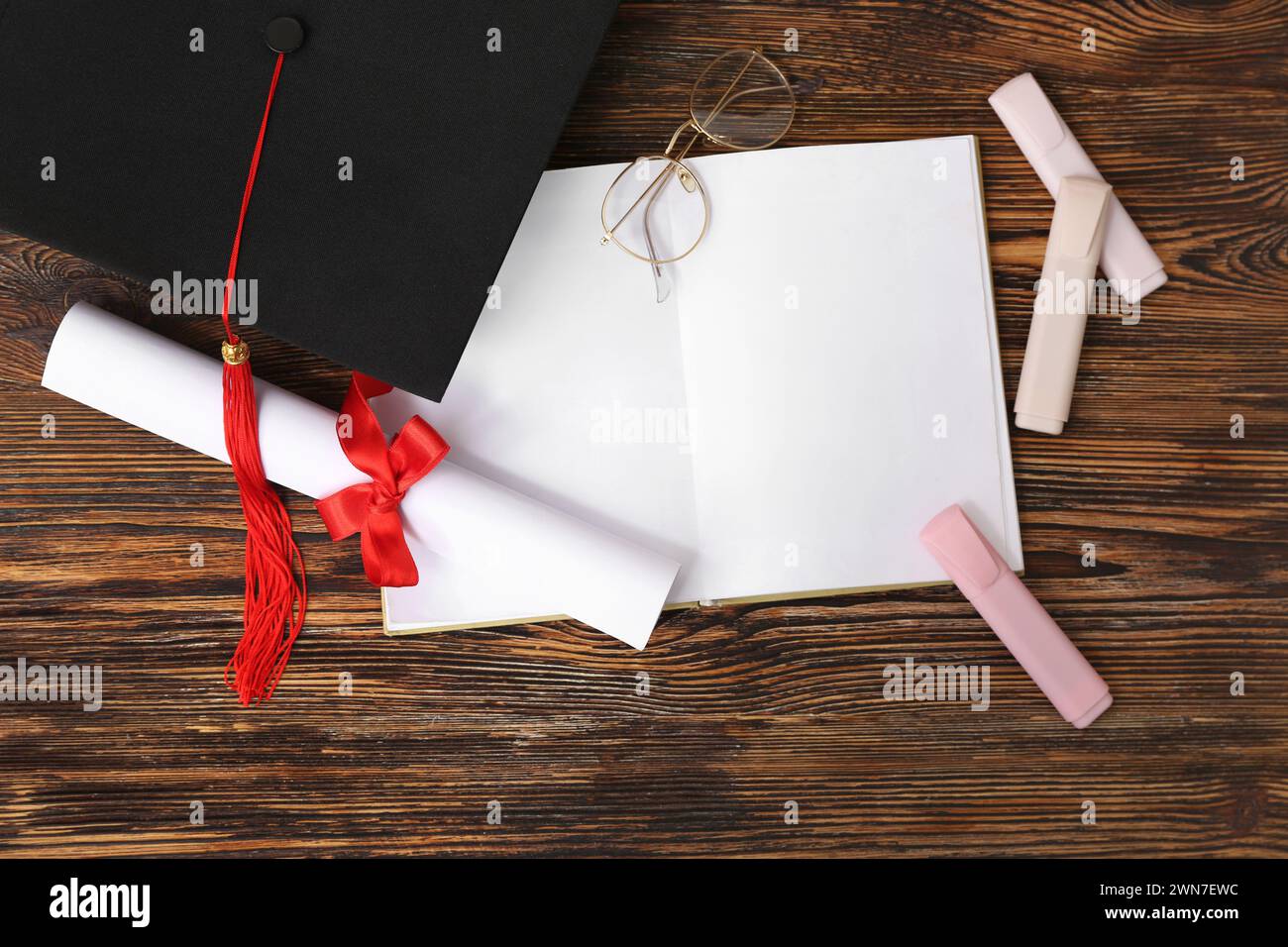 Bacheca con diploma, libro e occhiali su fondo in legno Foto Stock