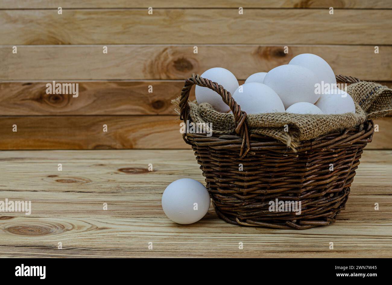 Uova di pollo bianco fresche in un cestino di legno di vimini. Il concetto di prodotti naturali alimenti sani aziende agricole biologiche. Giornata mondiale dell'uovo, festa di pasqua composit Foto Stock