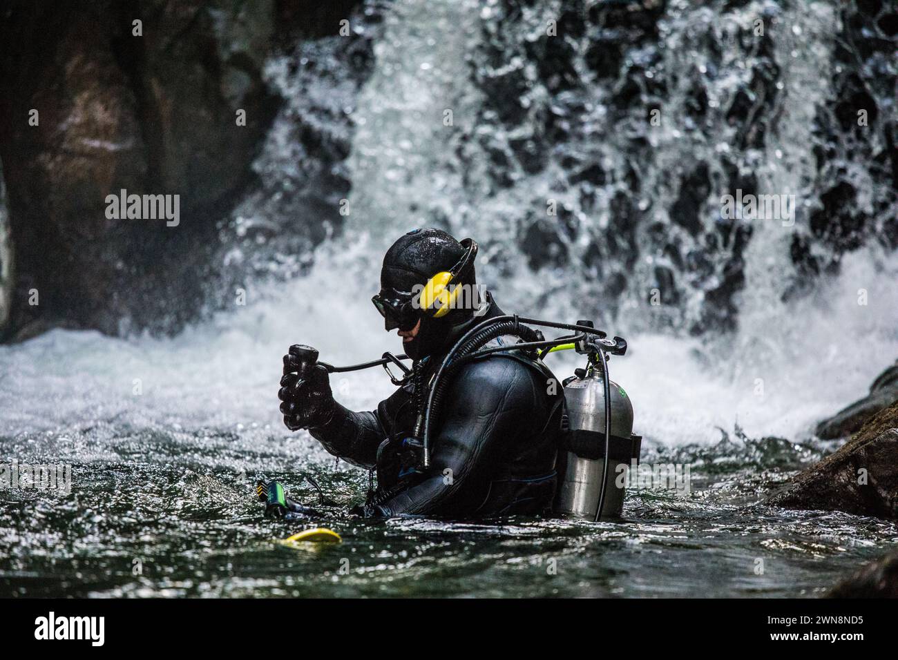 Le immersioni subacquee controllano il regolatore prima di immergersi sotto una cascata Foto Stock
