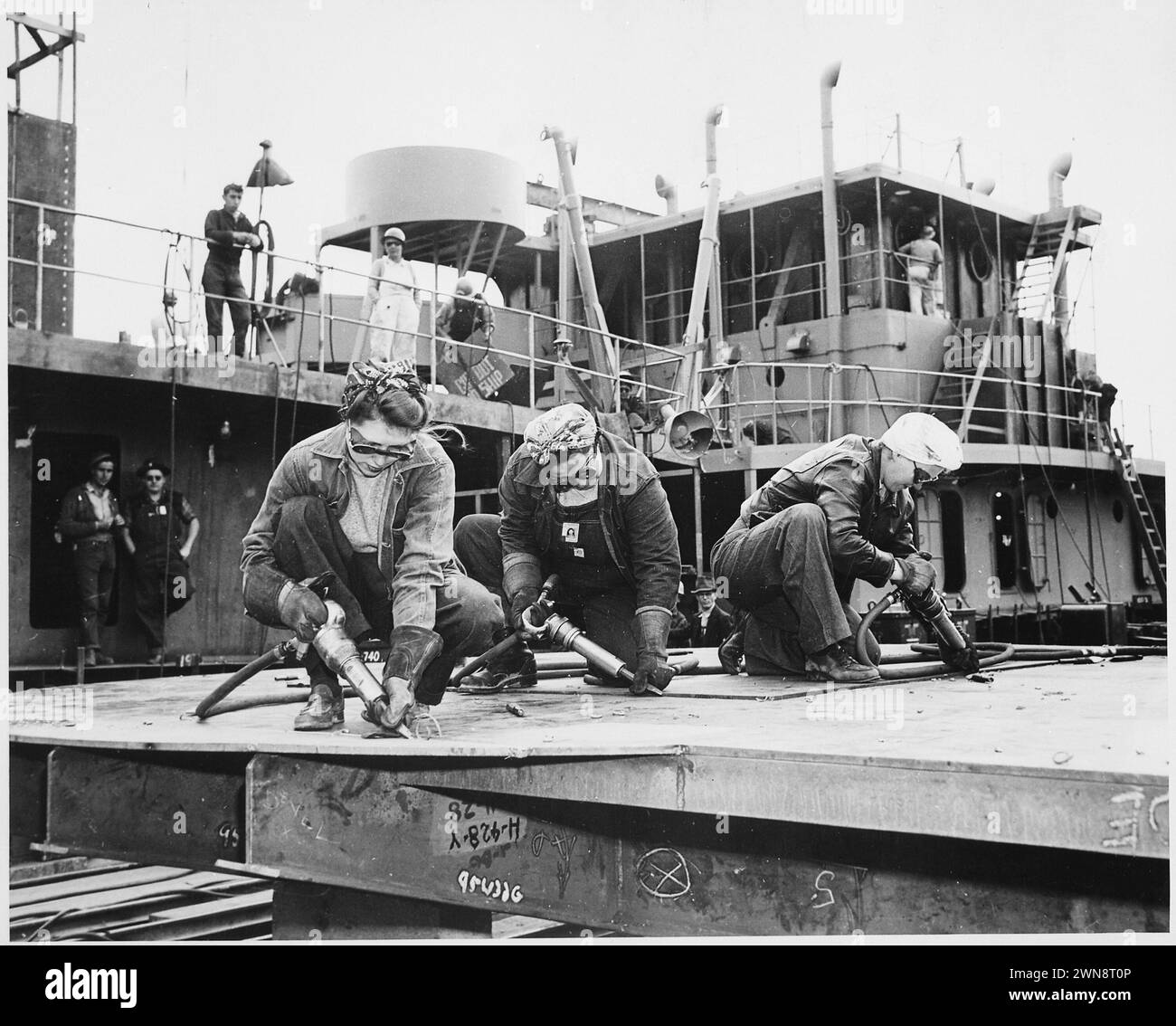 Fotografie d'epoca di donne che saldano parti di armi di profondità durante la seconda guerra mondiale, parte dell'importante contributo delle donne agli sforzi bellici. Peperoncini in un cantiere navale, costruzione navale, tre donne che lavorano/ 1942 Foto Stock