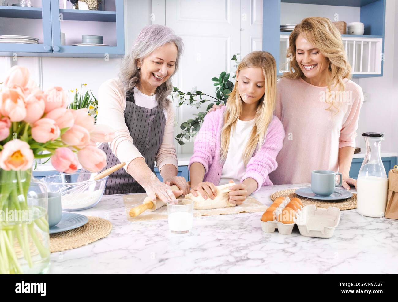Buona nonna anziana che insegna alla nonna carina con la mamma l'impasto per cucinare biscotti fatti in casa. La famiglia si diverte a trascorrere del tempo insieme Foto Stock