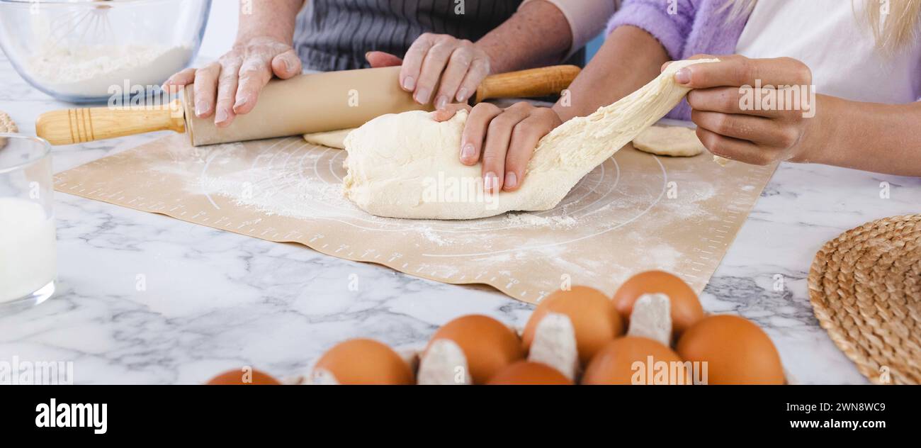 Madre che insegna alla figlia a preparare l'impasto usando farina e uova in cucina, a mani da vicino. Concetto di connettere generazioni di donne attraverso la cucina Foto Stock