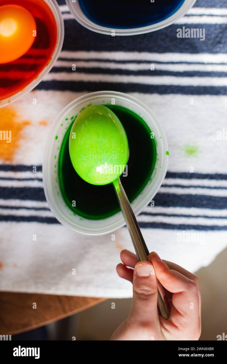 Uovo di Pasqua colorato verde su un cucchiaio di metallo Foto Stock
