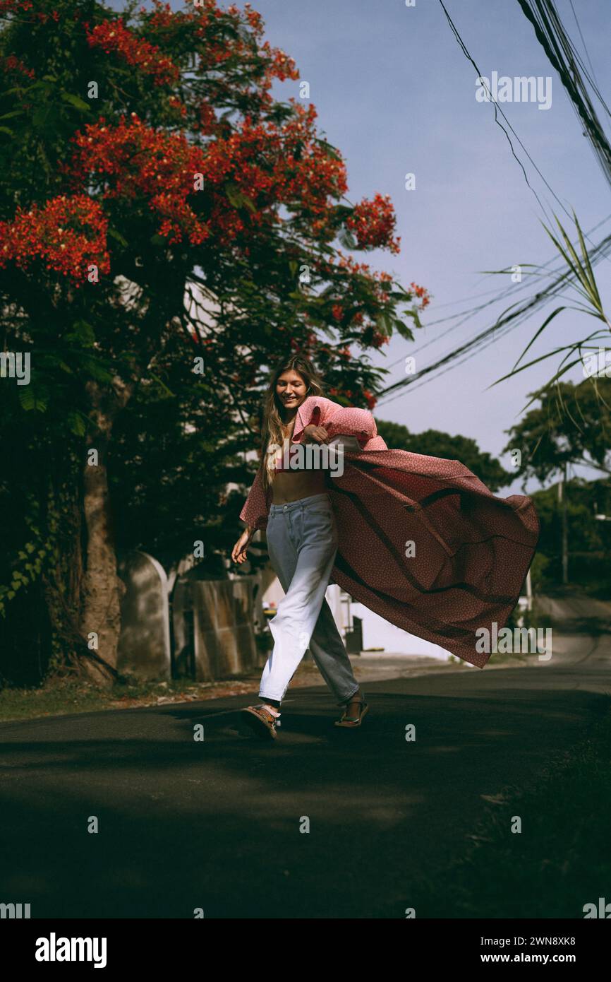La giovane donna con i capelli lunghi in un kimono cammina per la strada a Bali. Foto Stock