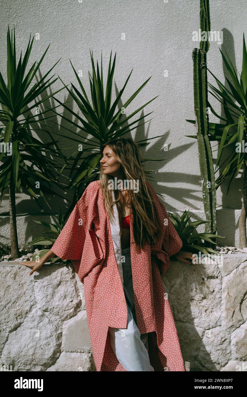 Una giovane donna con i capelli lunghi in un kimono tra i cactus. Foto Stock