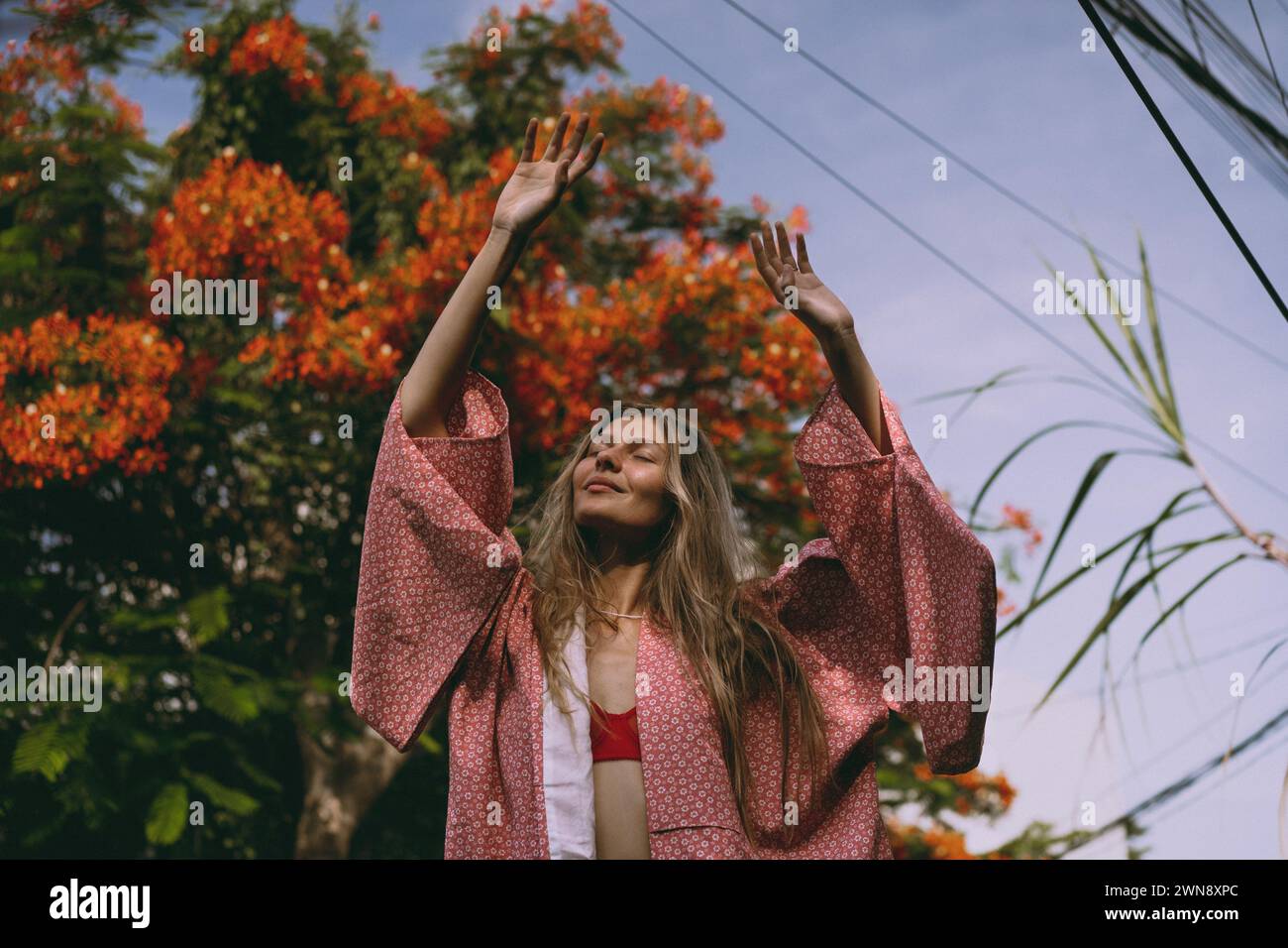 La giovane donna con i capelli lunghi in un kimono cammina per la strada a Bali. Foto Stock