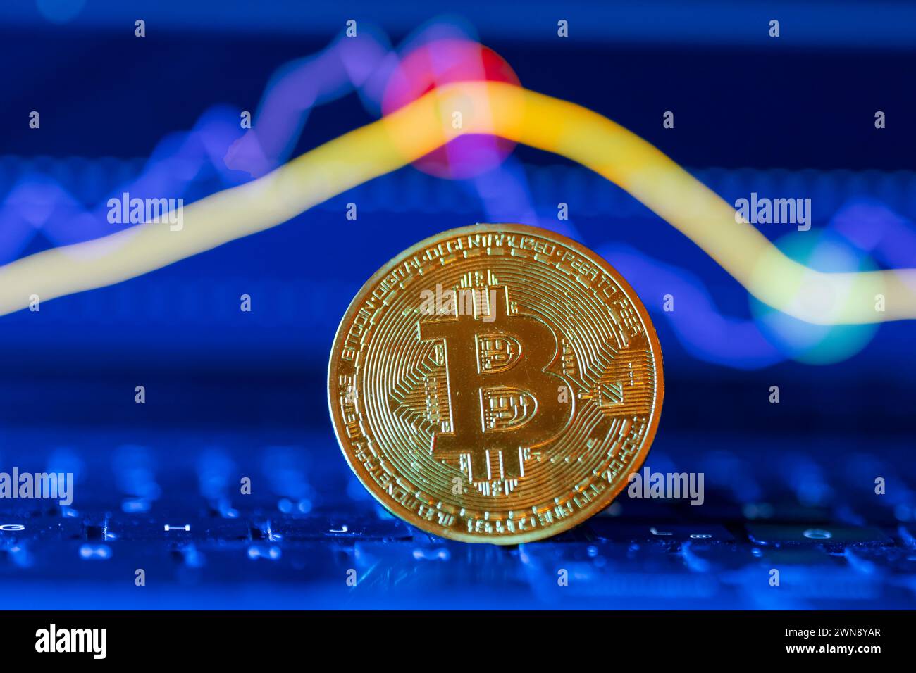 Moneta Bitcoin davanti a un grafico Foto Stock