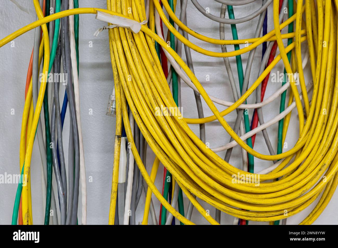 Vecchi cavi elettrici colorati appesi a una parete. Cavi a doppino intrecciato CAT5 per reti di computer. Foto Stock